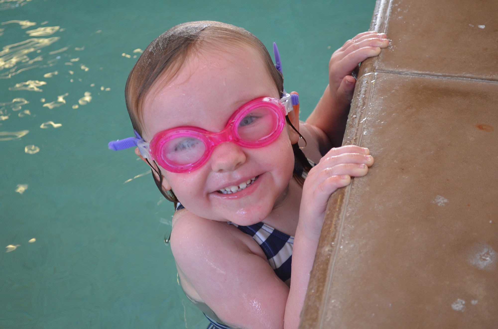 Young swimmer smiling at the pool edge
